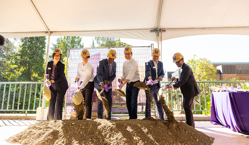 A group of people pose with shovels in hand at a groundbreaking event.