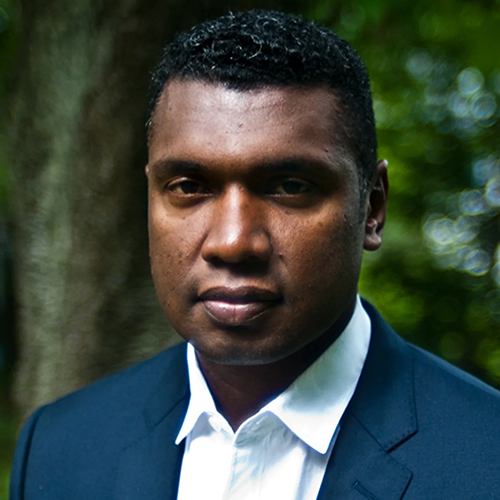 Dr. Stephon Alexander poses in front of a forest.