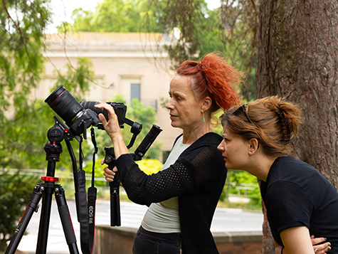 Juliet McMains and Samantha Stratman look at footage on a camera on a tripod during a dance rehearsal. 