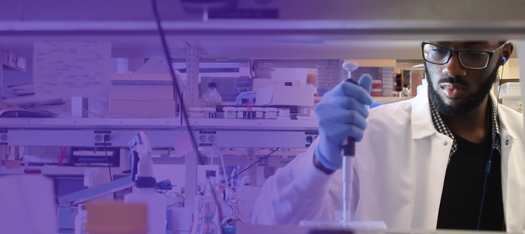 Student wearing a lab coat and working on a lab experiment